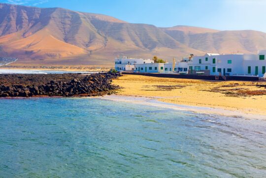 Le case bianche della Caleta de Famara sulla spiaggia, con il Risco alle spalle