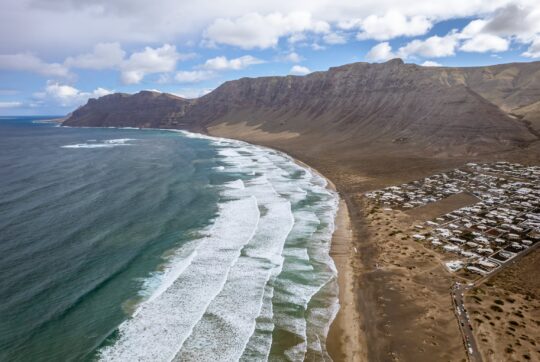 Playa de Famara dall’alto, con le onde e la parete del Risco de Famara